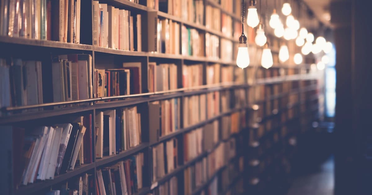 Kitaplar, defter ve masa lambasıyla düzenlenmiş bir çalışma masası